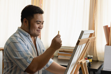 Young artist man creating or drawing front of canvas