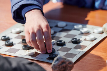 Outdoor draughts competition on paper checkerboard on table, close up players hands. Outdoor...