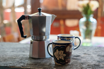 coffee maker on a table with mugs