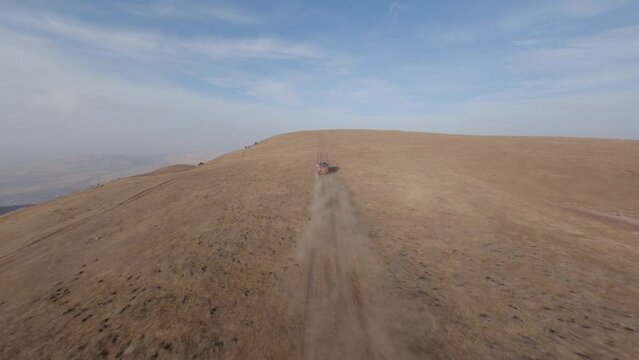 FPV sports drone follow shot SUV automobile race rally offroad riding desert mountain adventure sand splash. Aerial view cinematic hilly valley dirt road transportation extreme tourism exploration 4k
