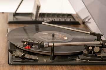 Turntable vinyl record player with vinyl records on a wooden table . black vinyl record