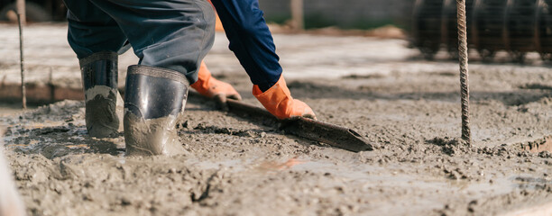Selective focus, Construction worker pouring cement and concrete. Worker leveling concrete floor with trowel. Banner © ME Image
