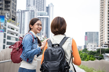 Happy young Asian students chatting and talk with each other after class standing outside. Women wear casual clothes to study near cityscape.