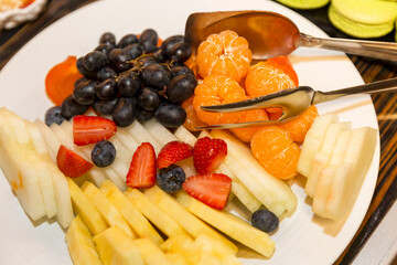 Fresh appetizing fruits and berries on a plate on the buffet table. Holidays, celebrations and business meetings. Close-up.