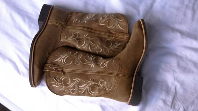 Panning shot of cowgirl boots on white sheet or background