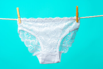 Female panties hanging on rope against blue studio background