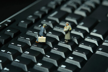 Miniature people toy figure photography. A military mail officer holding news pack envelope standing above keyboard