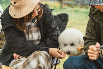 秋冬のキャンプ場で犬と一緒に料理を作るカップルキャンパー
