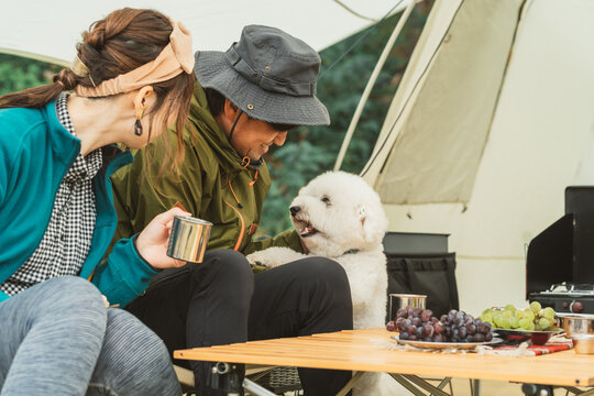 秋冬のキャンプ場で犬と一緒に料理を作るカップルキャンパー
