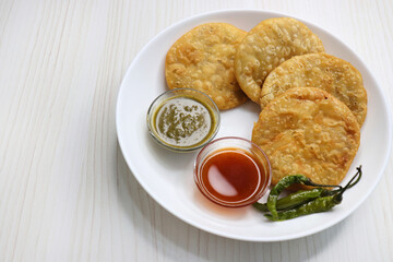 Shegaon Kachori or aloo pyaz ki kachodi served with green and red Chutney. Fried green chilies. it's a favorite Tea time snack, stuffed with lentils and spices mixture inside the dough. Deep fried.  - obrazy, fototapety, plakaty