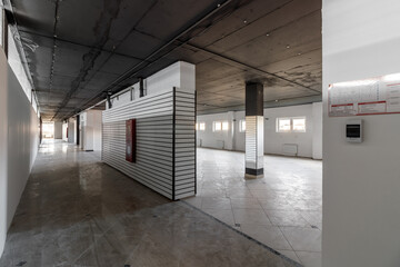 Empty retail space with a black ceiling and a dirty floor, immediately after repair