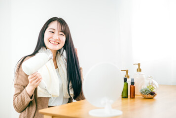 ドライヤーを使って髪を乾かす日本人女性（美髪）
