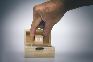 Hand pick wood block with us dollar icon in the treasure box.