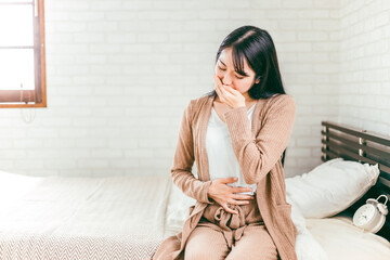 ベッドで腹痛・吐き気・咳・悪阻で悩む日本人女性
