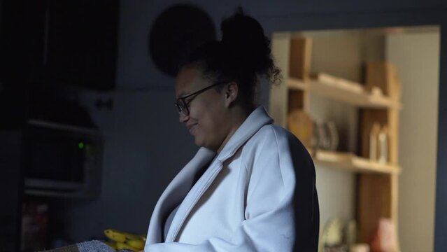 Smiling woman in the kitchen with beautiful backlight from the living room.