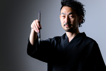 Image like a Japanese calligrapher「shodo」 holding a brush.