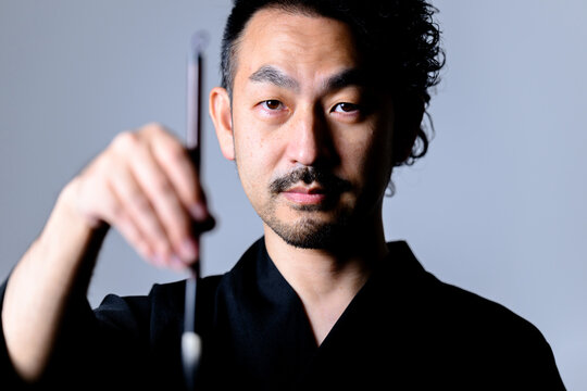 Image like a Japanese calligrapher「shodo」 holding a brush.