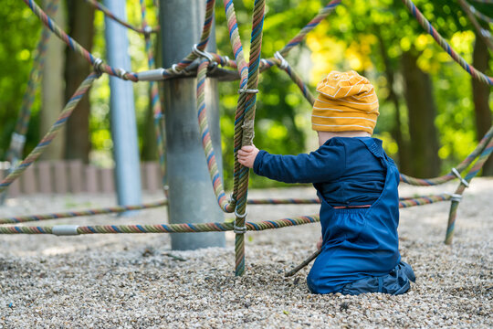 A baby plays on a climbing frame in a playground