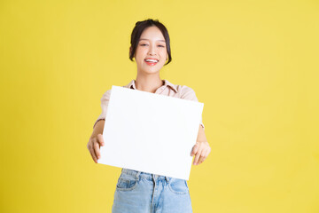 Obraz na płótnie Canvas image of a pretty asian girl holding a white billboard