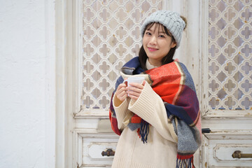 温かい飲み物を持ってこちらを見る笑顔の女性