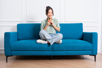 image of young Asian girl sitting on sofa at home