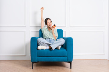 image of young Asian girl sitting on sofa at home