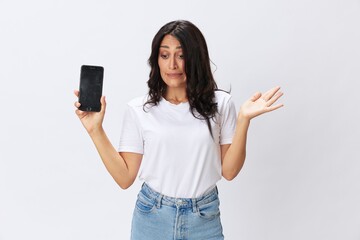 Fototapeta premium Woman blogger with a phone in her hands photo content, video call, selfie smile with teeth in a white t-shirt on a white background, copy space, emotions and gestures signals