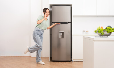 Fototapeta na wymiar Asian woman standing next to the refrigerator in the kitchen