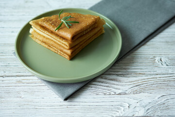 Pancakes on a plate with a sprig of rosemary. The concept is dinner time.