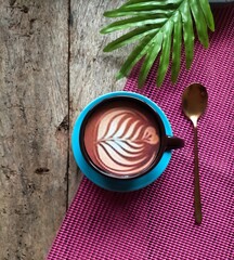 cup of coffee, spoon and leaf on wood and pink background 
