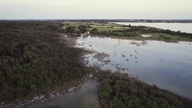 Beautiful aerial of irish lough corrib at the shore with small islands and grass covered fields. A small house near the water. Flying fowards during evening hour in summer. 4K