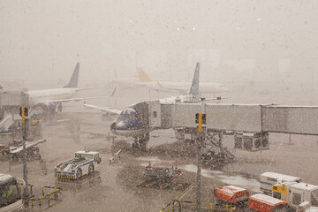 Busy airport view with airplanes and service vehicles at snowy winter day