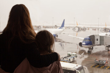 Family, mother and little doughter watching plane flying from airport