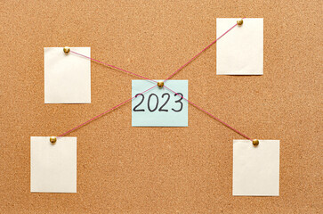 Blank paper notes are pinned to a cork board. Inscription 2023. The concept of detective...