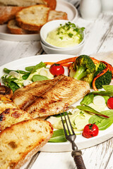 Close-up fried sea fish and vegetables. Tilapia fillet with broccoli, cherry tomatoes and lettuce....