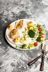 Baked sea fish fillet with vegetables. Tilapia fillet with broccoli, cherry tomatoes, fried potatoes, green peas and lettuce. Sea food on a white plate. Mediterranean Diet. Vertical shot. Copy space