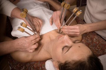 Holistic doctors working with woman touching by resonating tuning forks to special points of body
