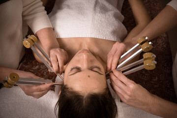 Hands of two healers working with female patient using tuning forks