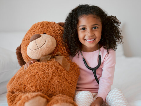 Stethoscope, teddy bear and girl with a child her stuffed animal with a smile in her house. Portrait of happy female kid holding a fluffy toy, learning to be a doctor or pediatrician in healthcare