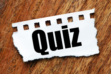The word QUIZ on a small piece of paper and a wooden table.