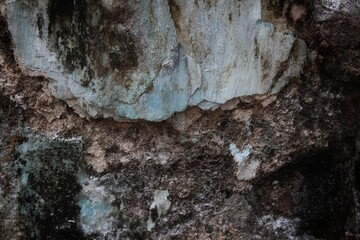 A weathered concrete wall with cracks and peeling paint, showing signs of age and decay.