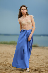 Fototapeta na wymiar Gentle woman in long blue skirt and lace blouse on the beach
