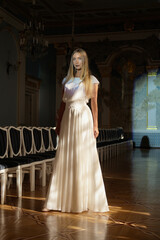 Fototapeta premium Full length portrait of beautiful young woman in ivory silk dress