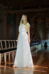 Obraz premium Beautiful young woman in white silk dress