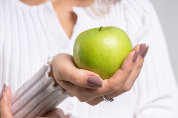 Graceful female hands holding a green apple close-up