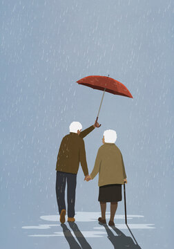 Affectionate senior husband holding umbrella over wife in rain
