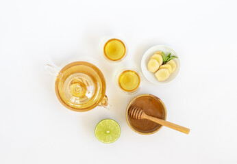Top view of a cup of tea with ginger root, lime, cinnamon and teapot on white background. Health drink concept..