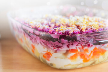 Layered salad herring under fur coat on table. Portion of traditional russian salad with herring, beet ,carrot and egg