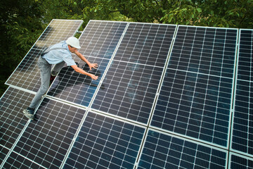 Aerial view of man technician installing photovoltaic solar panels to high steel platform. Concept...