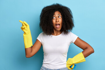 Attractive young female, standing isolated over blue background with positive surprise face and pointing the finger to copy space